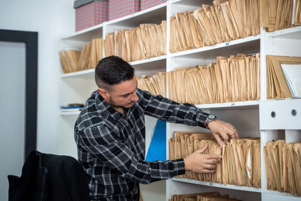 Man filing through folders on shelves